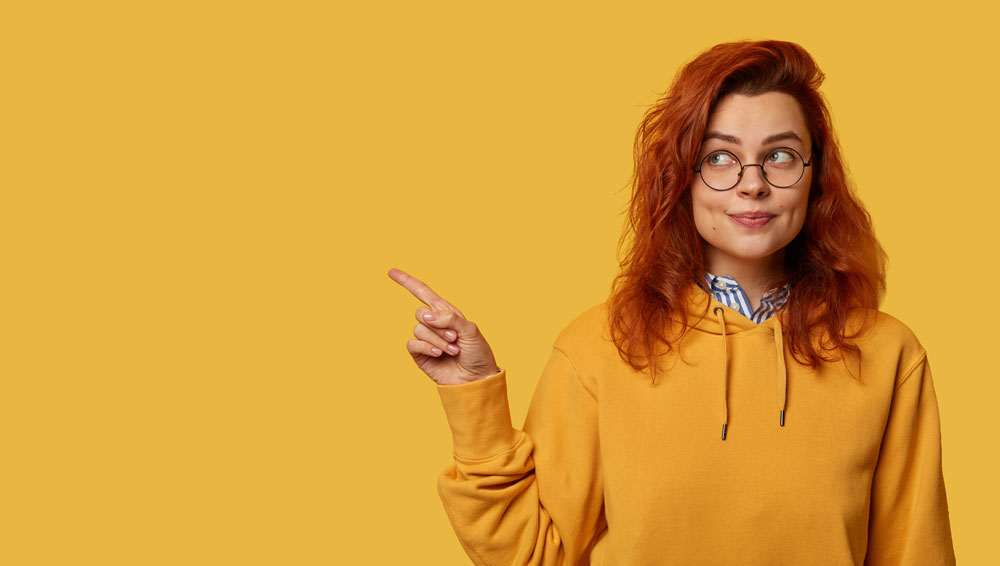 Rothaariges Mädchen zeigt mit dem Zeigefinger nach links